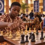 A beginner’s hands calmly move a knight towards the centre on a wooden chessboard in a crowded Nigerian tournament hall, with softly blurred players.