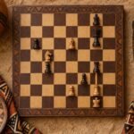 An overhead flat-lay photograph of a chessboard showing a knight attacking two pieces, a bishop pinning a piece to a king and a rook skewering a.