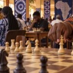 A player's hands complete kingside castling on a wooden chessboard in a busy Nigerian chess hall, with the king and rook sharp in the foreground,.