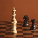 A documentary-style chess photograph in warm natural light, showing a wooden board with three white heavy pieces aligned on the c-file against a dark.